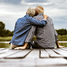 Senior couple sits on the edge of a dock