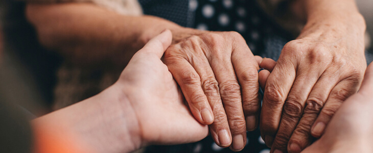 Young adult holds grandparent's hand