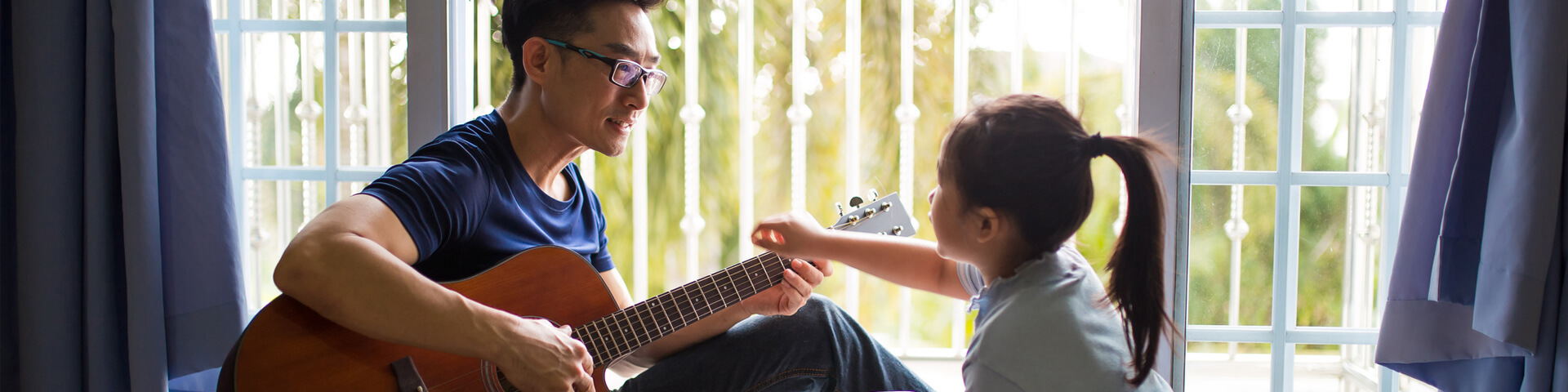 Father plays guitar with young daughter